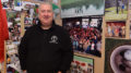 Al Holdren is pictured standing beside hundreds of photos of thousands of volunteers who participate in "Secret Families." Photo by Mike Rhodes.