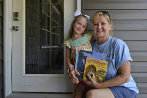 Four-year-old Isabelle Rabenstein receives books from Dolly Parton’s Imagination Library, delivered by letter carrier Debbie Edwards Thompson. Isabelle is the daughter of Jordan and Zach Rabenstein. Photo provided