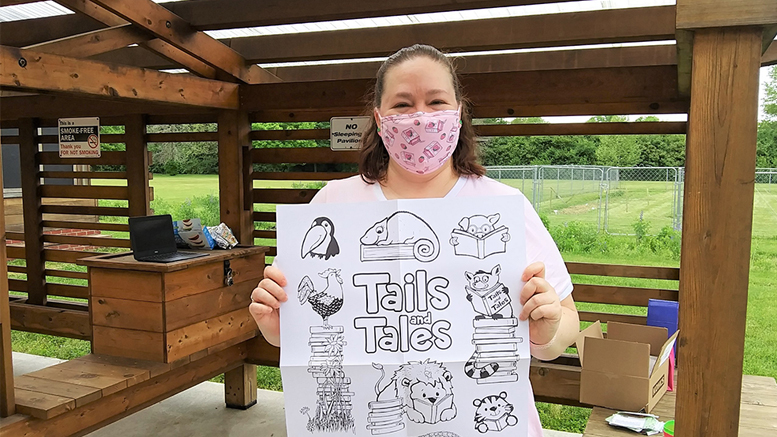 Shanna Hurd, Youth Services Supervisor at Maring-Hunt Library, displays a coloring poster for kids at a recent outdoor event. Photo by Susan Fisher