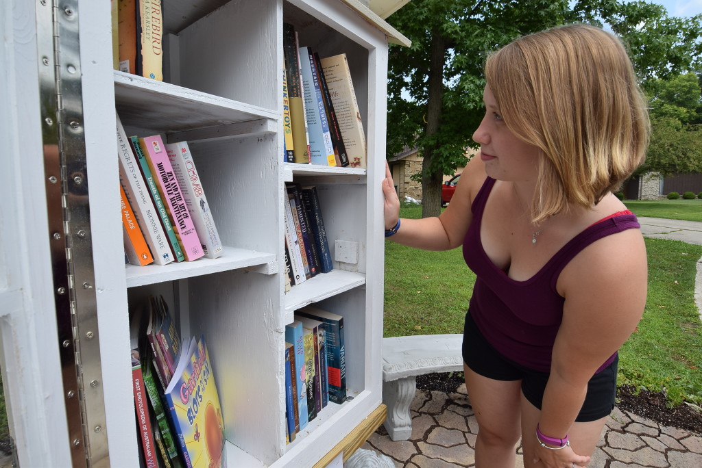 Elianor Priebe takes a look at some of the books in the little free library in Johnson Woods addition. Photo: Mike Rhodes