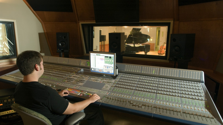 An audio engineer operating a digital audio mixing board is shown in this provided photo.