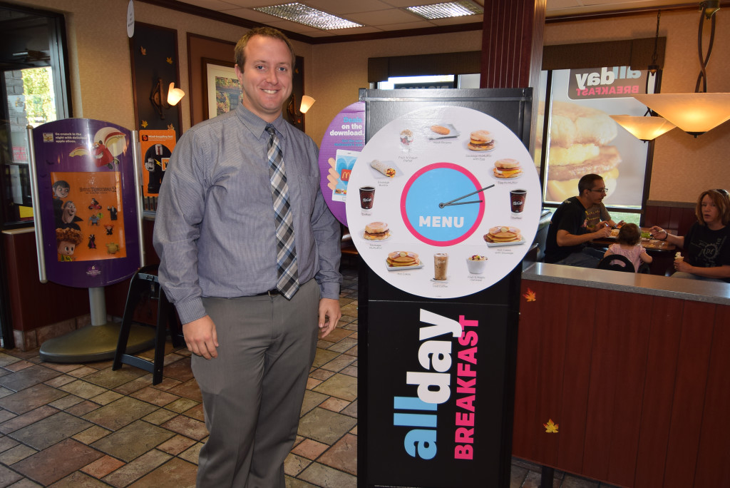 Jonathan Terhune, area supervisor, stands beside a new in-store display of the all day breakfast menu. Photo by: Mike Rhodes