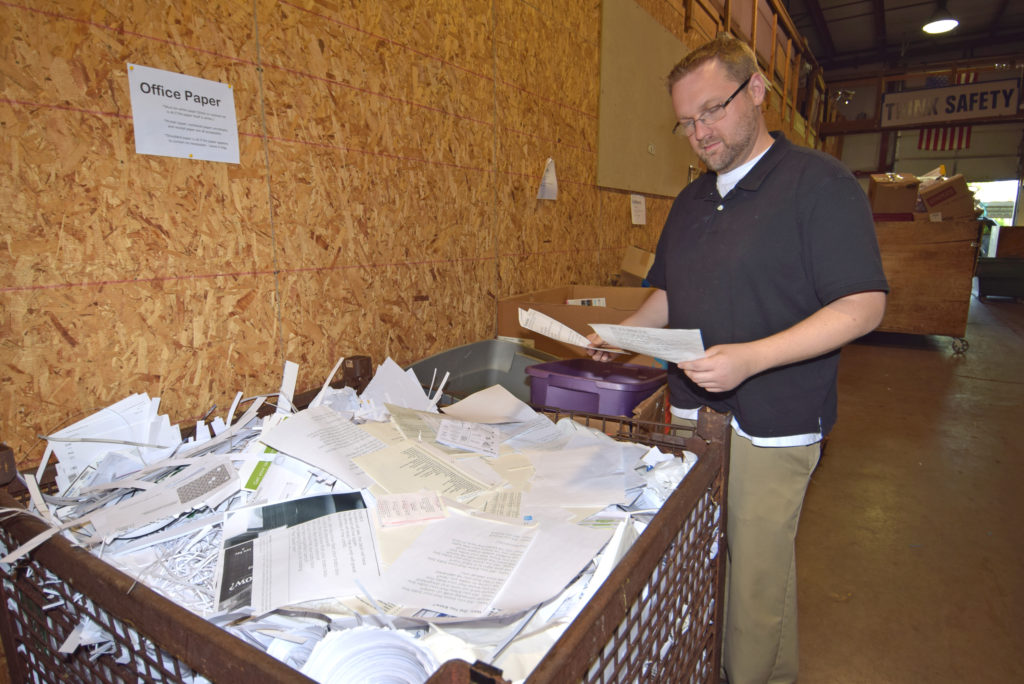 Ryan Hart examines some of the paper products used for recycling. Photo by: Mike Rhodes