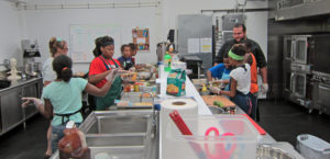 Inside Out’s Community Kitchen is crowded with eight young chefs at work. Photo by: John Carlson
