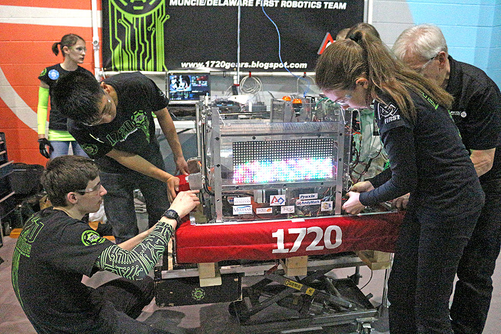 Team members working on the PhyXTGears robot in the pits. Photo includes Jessica Van Ness, Ethan Nguyen, John Pugsley, Moriah Schlenker and mentor, Mike Koch.