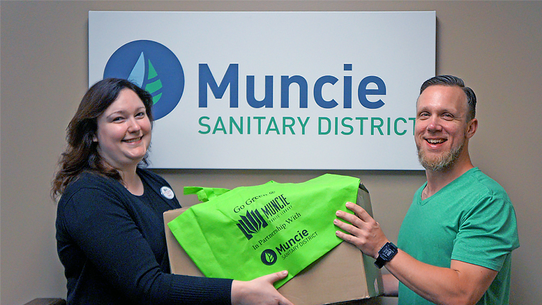 MPL employee Sara McKinley and MSD employee Jason Donati look at reusable tote bags made possible by a partnership between Muncie Public Library and Muncie Sanitary District. Photo by: Loren McClain, Muncie Public Library