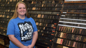 Kim Miller, owner of Tribune Showprint, is pictured in front of the "type wall" inside her shop at MadJax. Photo by: Mike Rhodes