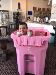 Adam Hale smiles as he stands inside one of the food drive collection totes for Feed My Sheep. Heidi J Hale Designs, 301 S. Walnut St., is one of about 50 locations that are collecting food for the 22nd annual Feed My Sheep Thanksgiving Day Dinner. The event provides free hot meals and a bag of groceries to over 1,500 needy residents every year. Photo provided.