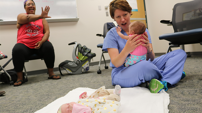 Dr. Melanie Schreiner, associate director at the IU Health Ball Memorial Family Practice and medical director of the CenteringPregnancy program, holds baby Artemis as she waves to her mother, Miranda. CenteringPregnancy is an innovative model of prenatal care that facilitates interactive learning and community building in a group setting. Photo provided.