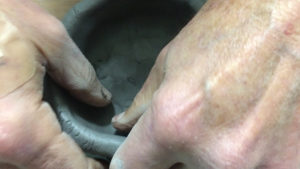 Fingers shape a lump of clay by the pinch pot method. Photo by: Nancy Carlson