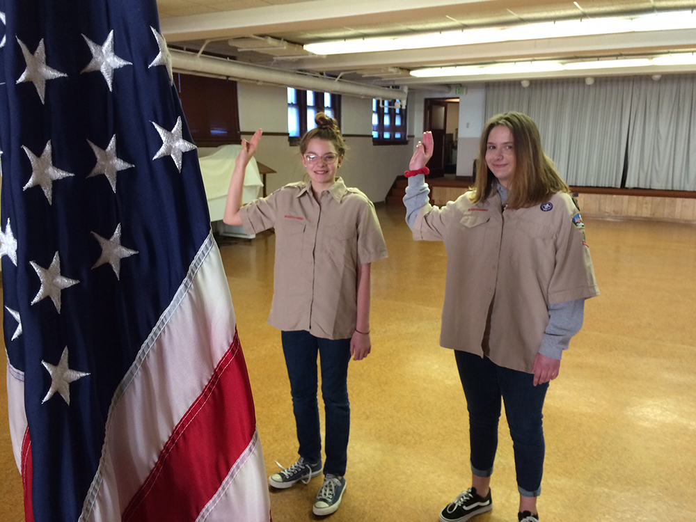 Scouts Anneka Tschuor (left) and Moira Teal pledge allegiance to our flag. Photo by: John Carlson