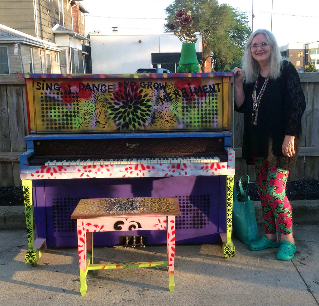 Debra Gindhart poses with her finished piano art, titled Sing, Dance and Grow Merriment, at an unveiling event on June 28, 2019 at Madjax. Photo provided