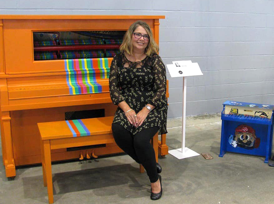 Denise King poses with her finished piano, titled Chromesthesia, at at Madjax's Second Thursday event on July 11, 2019. Photo provided