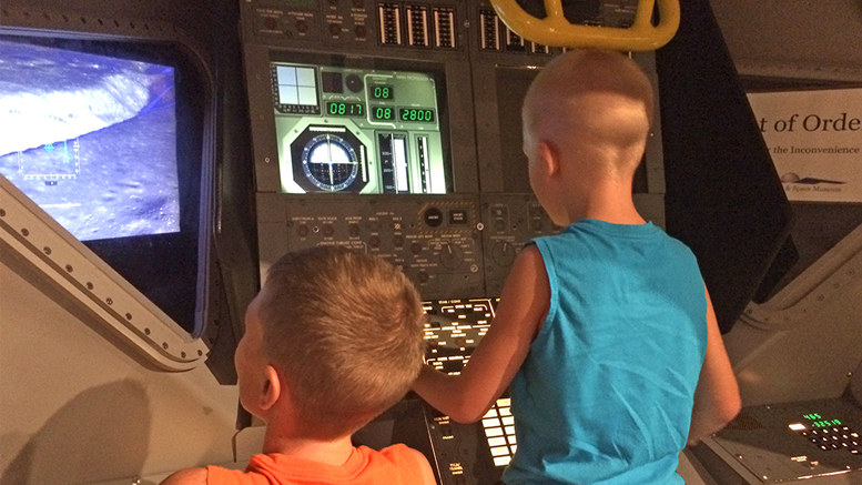 Two young museum visitors fly a lunar landing simulator. Photo by: Nancy Carlson