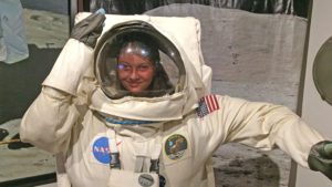 A young lady takes a look through an astronaut’s helmet. Photo by: Nancy Carlson