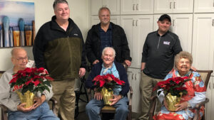 Woof Boom Radio staff members Mitch Henck, Brian Casey, and Zack Johnson are pictured with Sugar Fork Crossing nursing home residents during a Project Poinsettia delivery. Photo by: Lindsey Martin