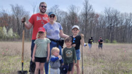 A family poses with their shovels at Red-tail’s 2022 Earth Day Tree Planting. Photo by Red-tail Land Conservancy.