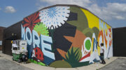 Volunteers continue work on the 'More Love' mural on south Walnut street. Photo by Mike Rhodes