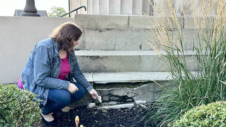 Sara McKinley, Local History & Genealogy Supervisor at Carnegie Library, points out damaged exterior cement steps. Photo by Spenser Querry, Muncie Public Library